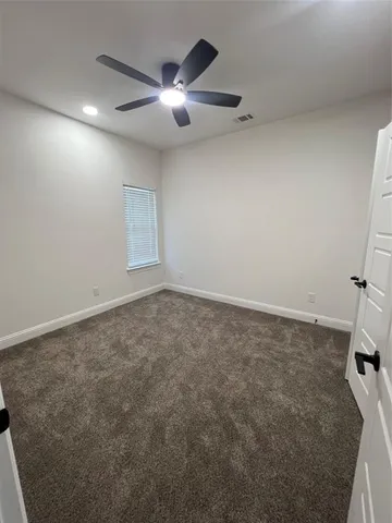 en empty room with ceiling fan and window