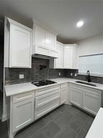 a kitchen with white cabinets sink and stove