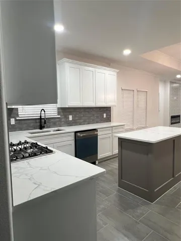 a kitchen with stainless steel appliances a sink dishwasher a stove and white cabinets
