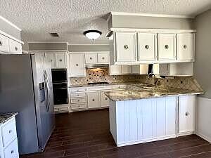 3206 77th Street Lubbock, TX 79423 - Photo 12 of 35 a kitchen with stainless steel appliances granite countertop a refrigerator a stove and white cabinets
