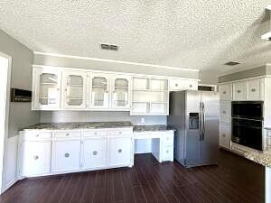 3206 77th Street Lubbock, TX 79423 - Photo 8 of 35 a kitchen with granite countertop a stove a sink dishwasher a refrigerator and white cabinets with wooden floor