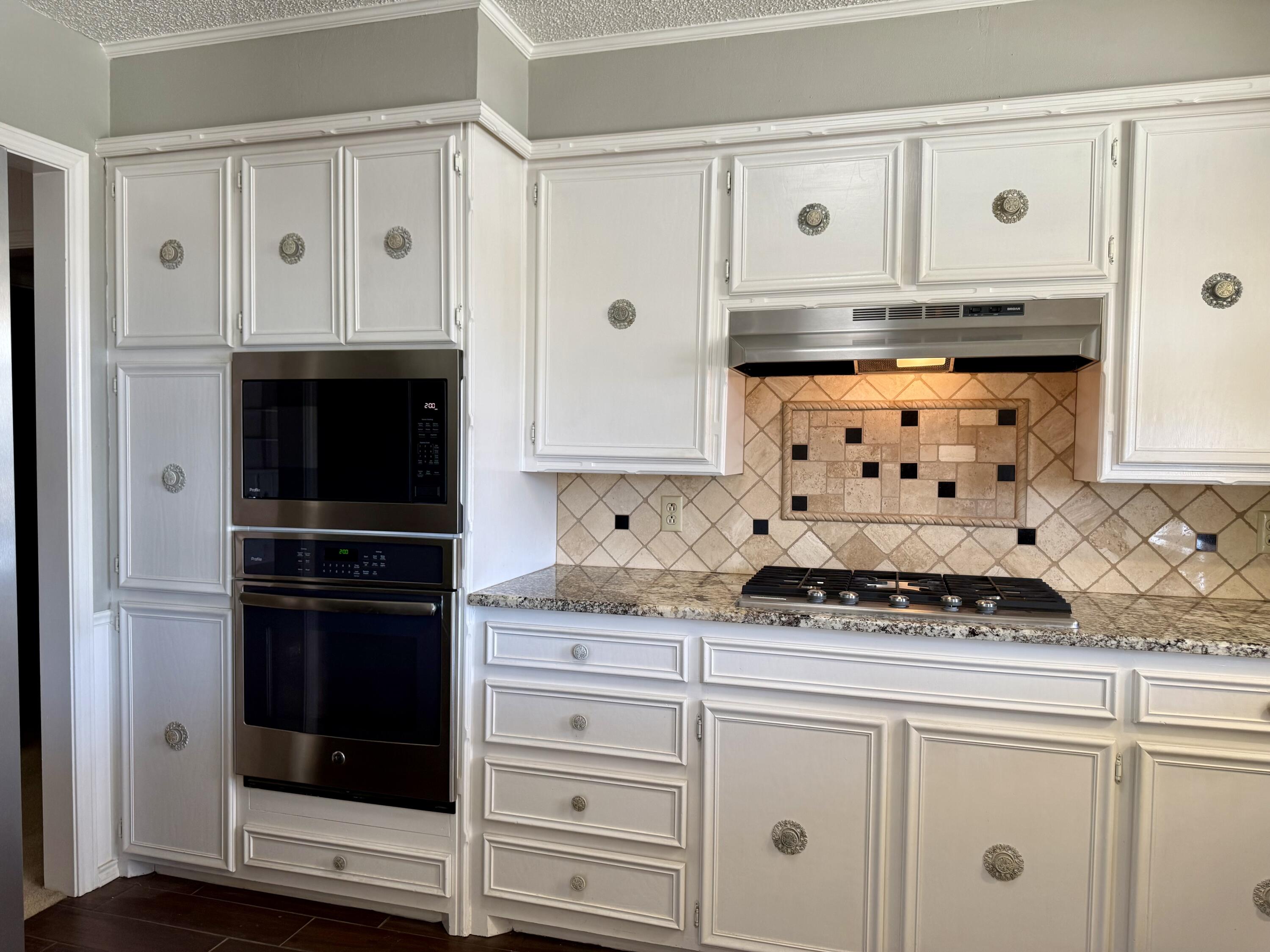 3206 77th Street Lubbock, TX 79423 - Photo 10 of 35 a kitchen with granite countertop a stove and a microwave