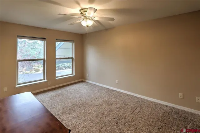 an empty room with windows and fan