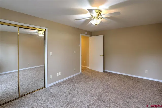 an empty room with closet and a chandelier fan
