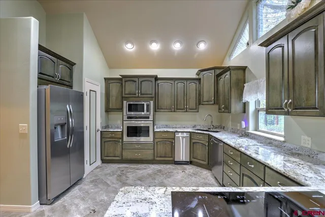 a kitchen with stainless steel appliances granite countertop a refrigerator and a sink