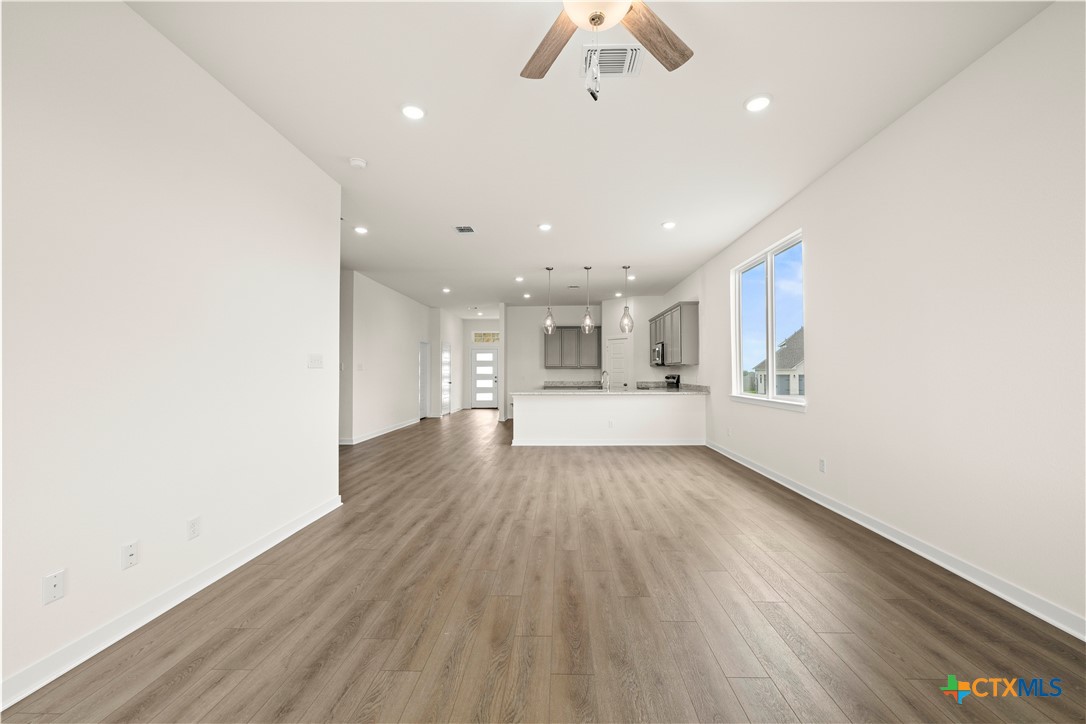 5102 Pollack Lane Belton, TX 76513 - Photo 28 of 30 an empty room with wooden floor kitchen view and windows
