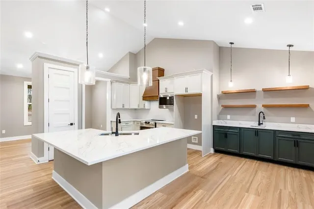 a kitchen with stainless steel appliances kitchen island granite countertop a sink a stove and a wooden floors