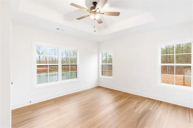an empty room with wooden floor fan and windows