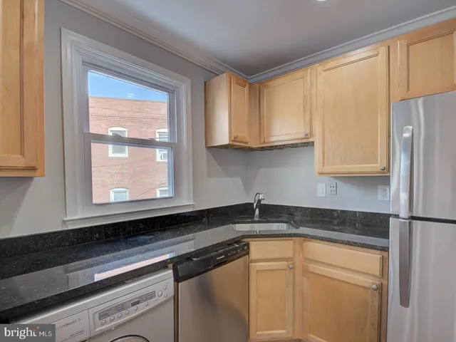 a kitchen with stainless steel appliances granite countertop white cabinets sink and a granite counter top