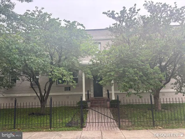 a front view of a house with a garden and tree