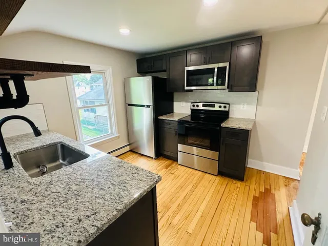 a kitchen with stainless steel appliances kitchen island granite countertop a refrigerator stove and sink