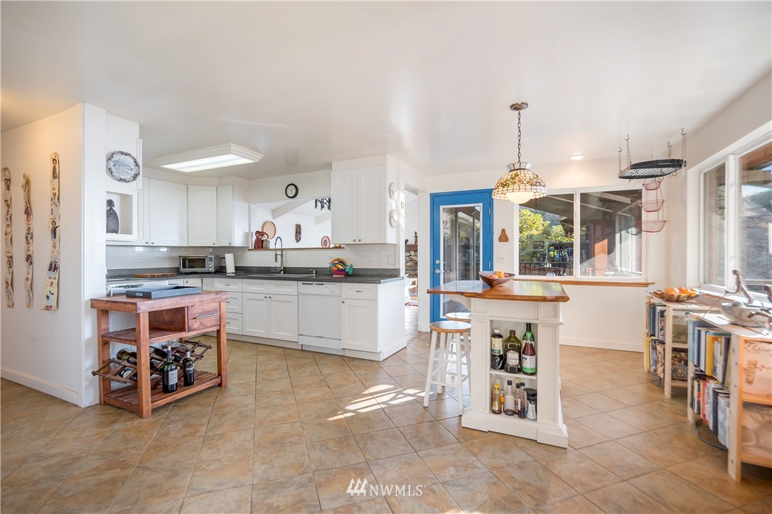 731 Woodmont Beach Road South Des Moines, WA 98198 - Photo 9 of 40 a kitchen with stainless steel appliances kitchen island granite countertop a table chairs and a refrigerator
