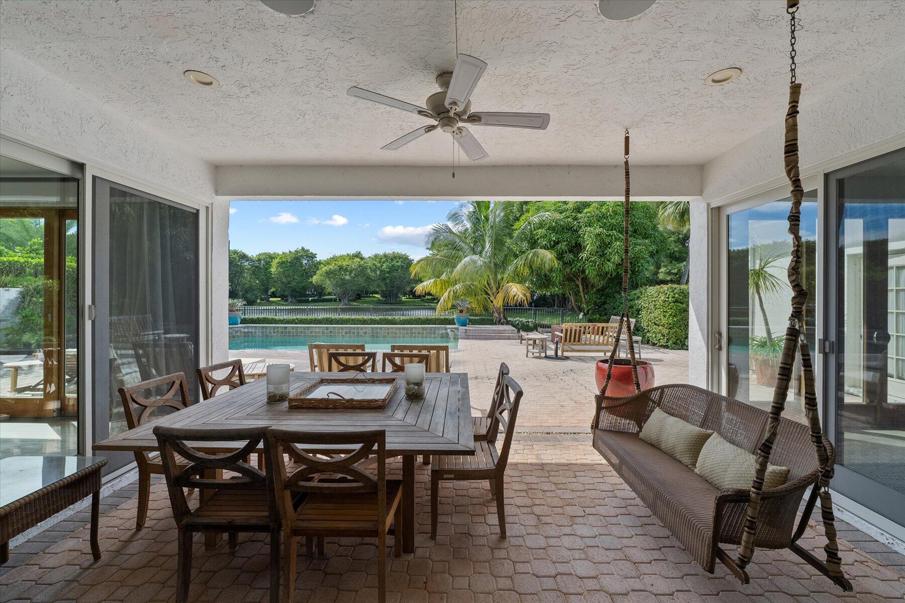 2821 Bent Cypress Road Wellington, FL 33414 - Photo 53 of 64 a view of a patio with a table chairs and a floor to ceiling window