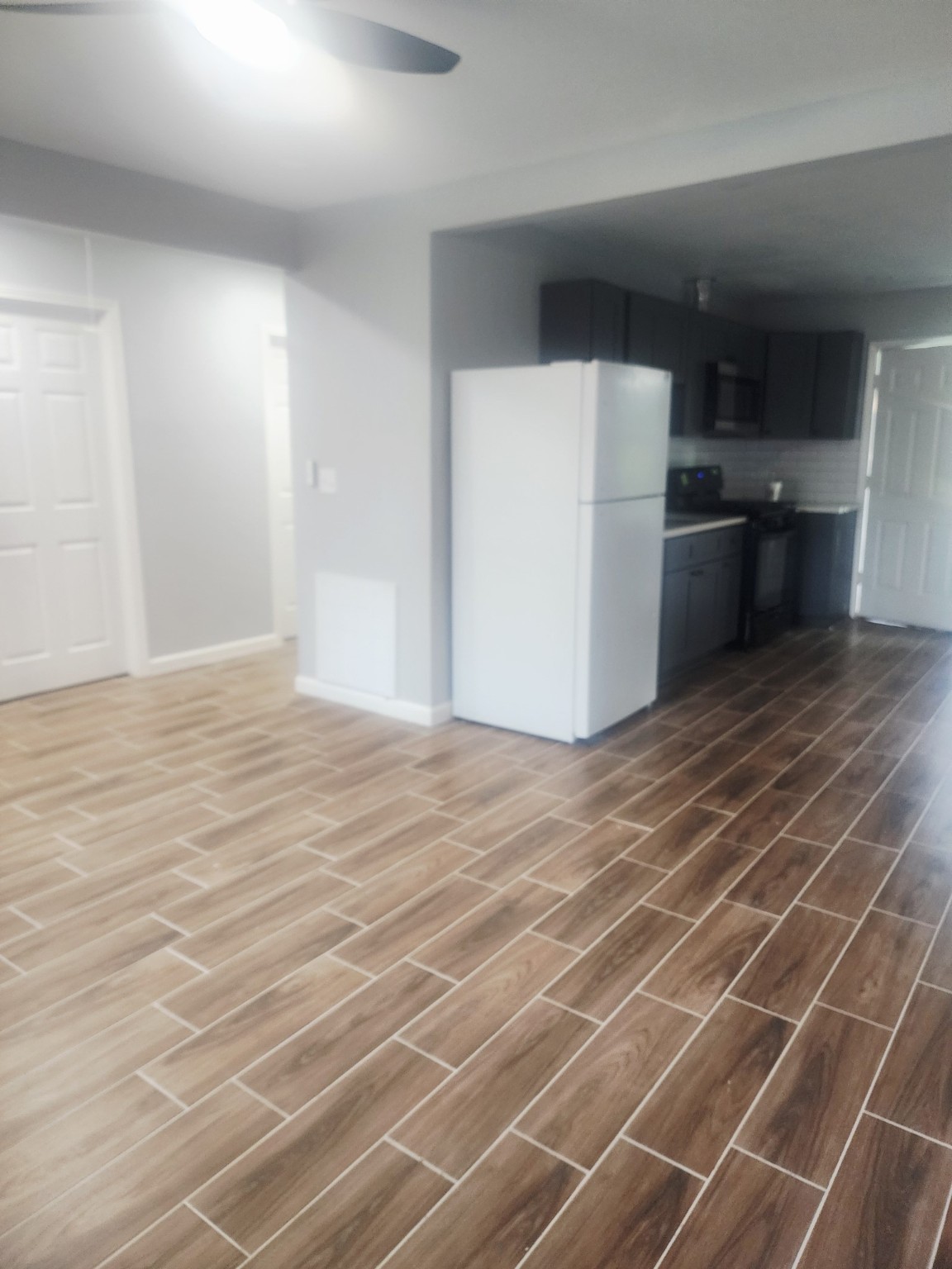 3934 Alice Street Houston, TX 77021 - Photo 3 of 9 an empty room with wooden floor and a kitchen