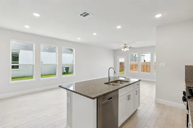 a kitchen with granite countertop kitchen island a sink appliances and a counter top space