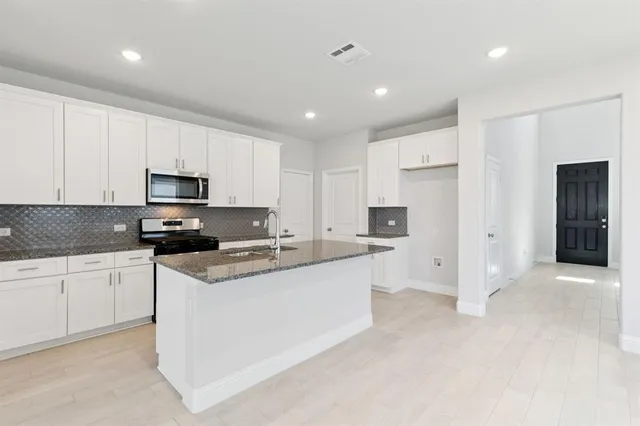 a kitchen with stainless steel appliances granite countertop a refrigerator sink and white cabinets