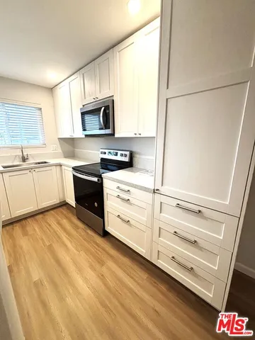 a view of kitchen with stainless steel appliances wooden floor and window