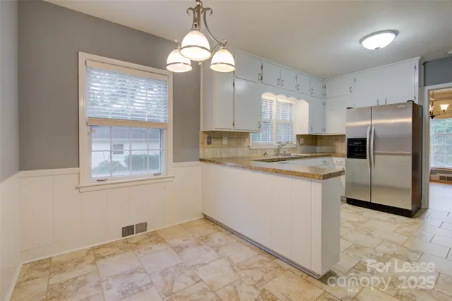 a kitchen with granite countertop a refrigerator a sink a center island and cabinets