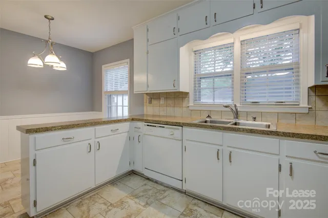 a kitchen with granite countertop a sink and white cabinets