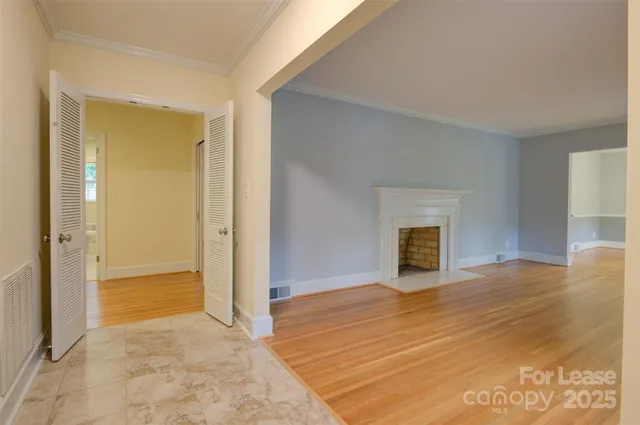 a view of an empty room with wooden floor and a fireplace
