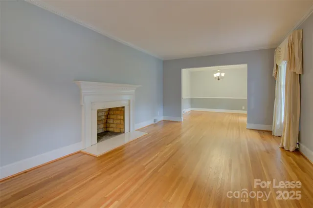 a view of empty room with wooden floor and fireplace