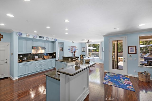 a kitchen with stainless steel appliances granite countertop a stove top oven a sink and a refrigerator