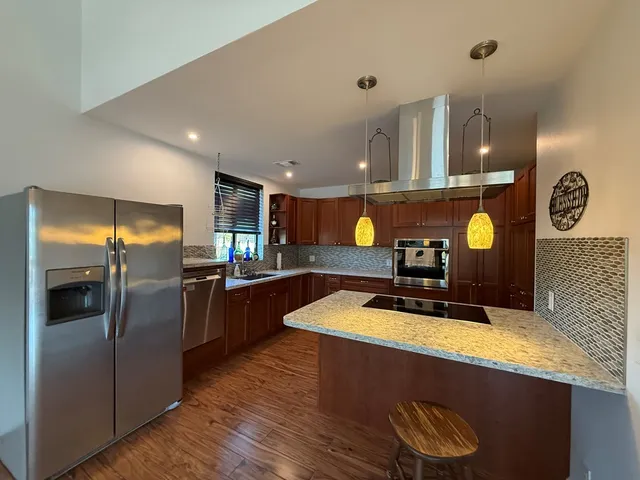 a kitchen with stainless steel appliances granite countertop a sink a stove and a refrigerator