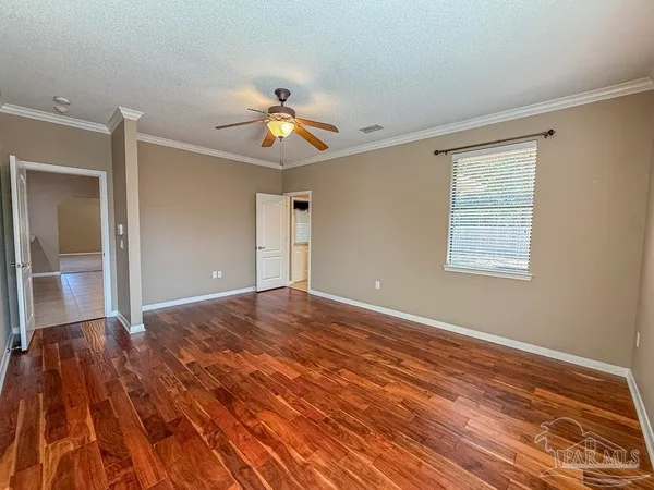 a view of empty room with wooden floor and fan