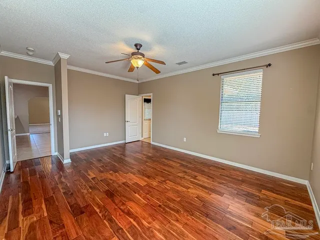 a view of empty room with wooden floor and fan
