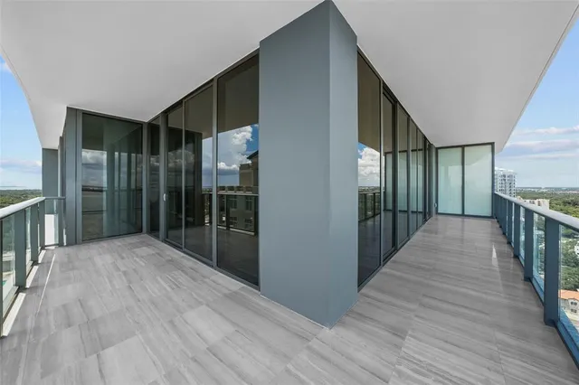 a view of an empty room with wooden floor and windows