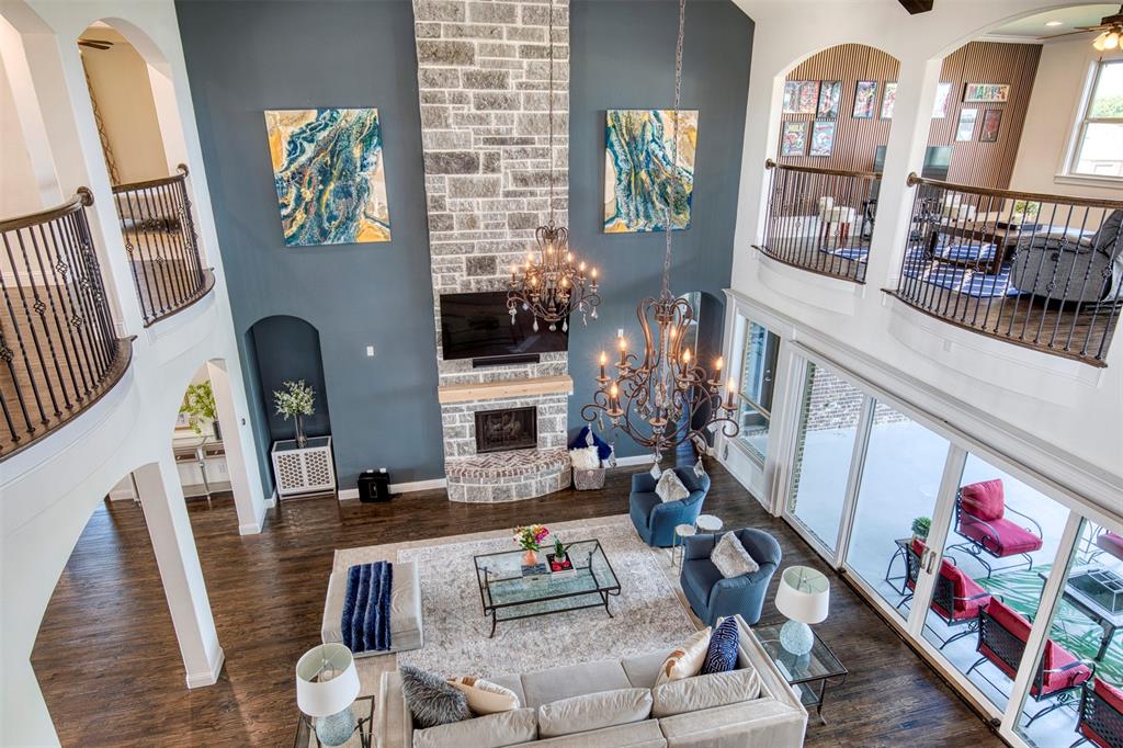 901 Inverness Court Lucas, TX 75002 - Photo 34 of 40 Living area featuring arched walkways, a stone fireplace, dark wood-type flooring, and a high ceiling
