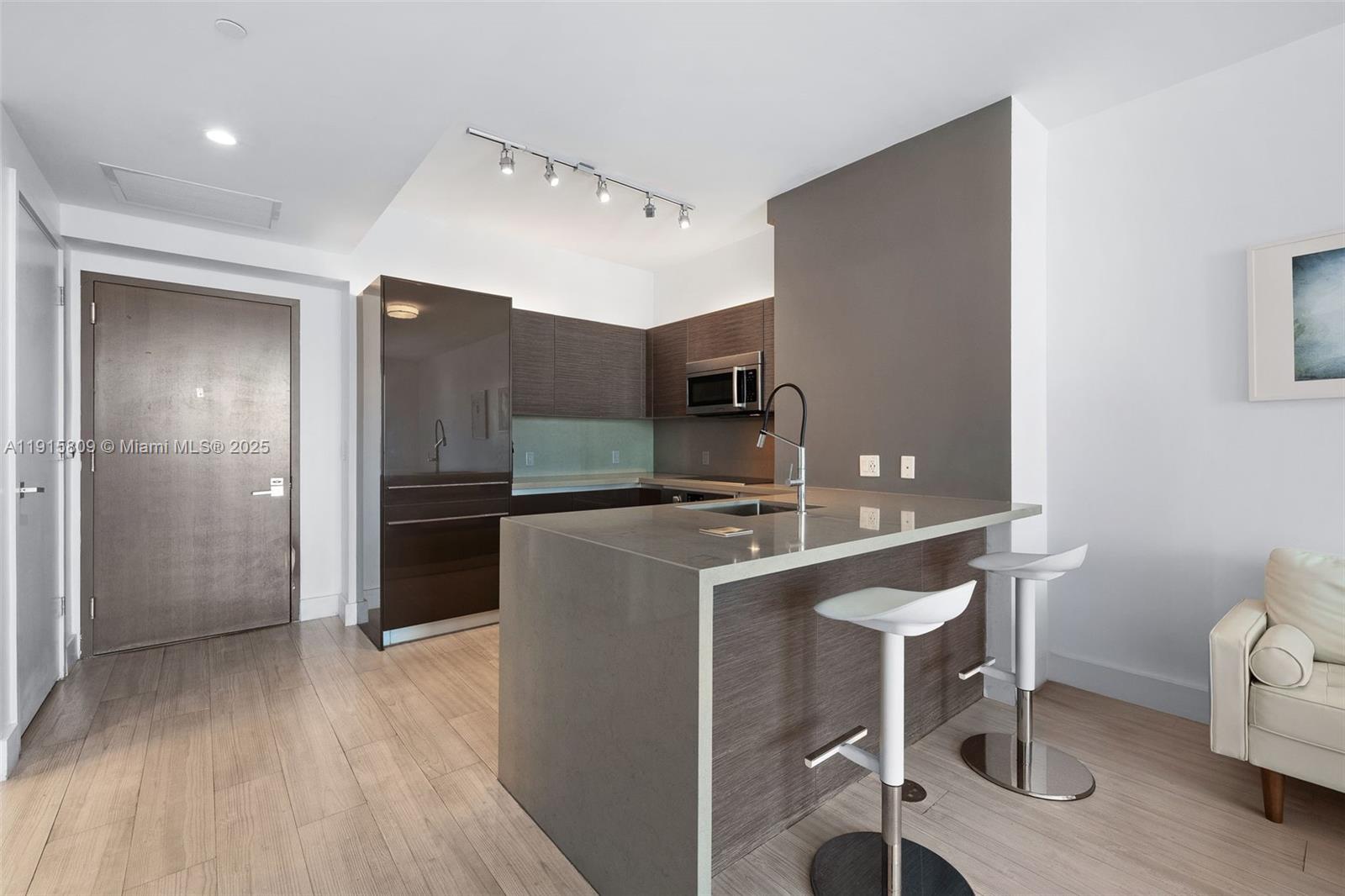 1080 Brickell Avenue, Unit 3705 Miami, FL 33131 - Photo 15 of 32 a kitchen with kitchen island a counter top space a sink stainless steel appliances and cabinets