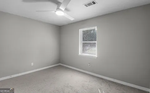an empty room with a ceiling fan and carpet