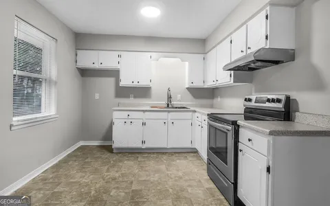 a kitchen with granite countertop white cabinets and white appliances
