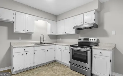 a kitchen with granite countertop white cabinets and a window