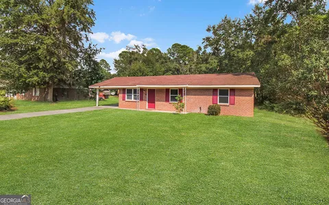 a view of a house next to a big yard and large trees