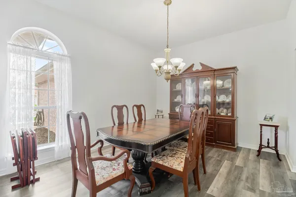 a dining room with furniture a chandelier and wooden floor