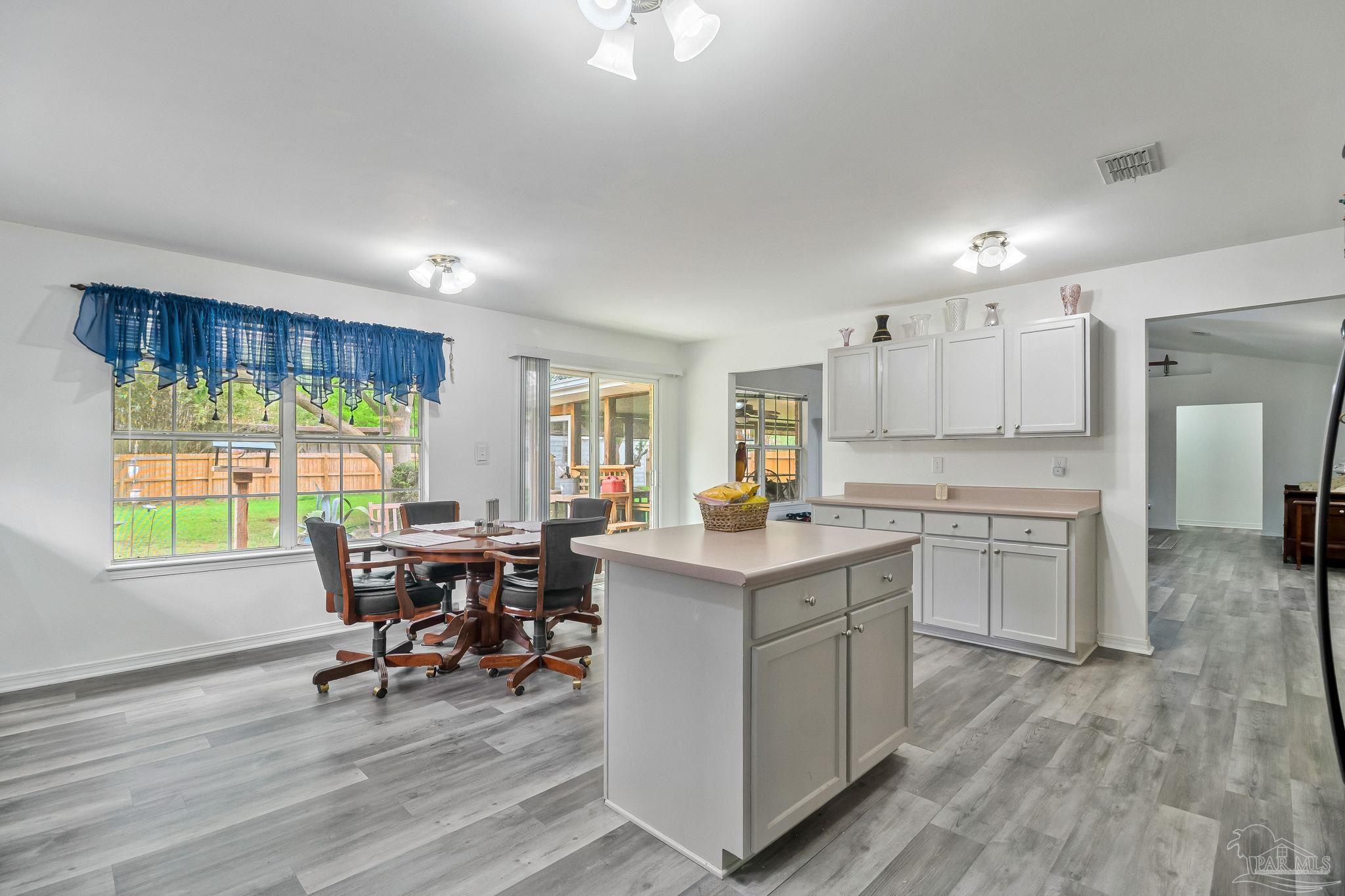 5691 Berrybrook Circle Pace, FL 32571 - Photo 6 of 22 a kitchen with kitchen island granite countertop wooden floors and white cabinets
