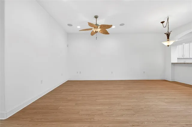 a view of a room with a ceiling fan and hardwood floor