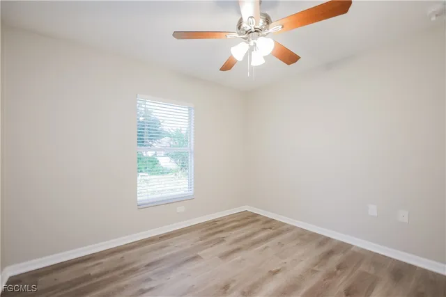 an empty room with a window and a fan