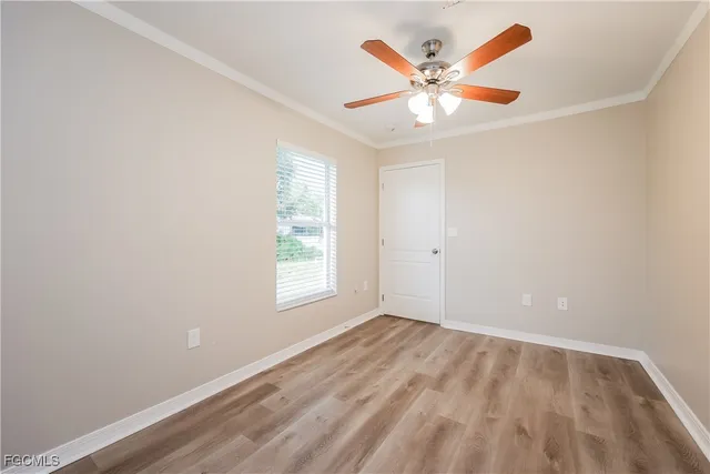 an empty room with ceiling fan and window