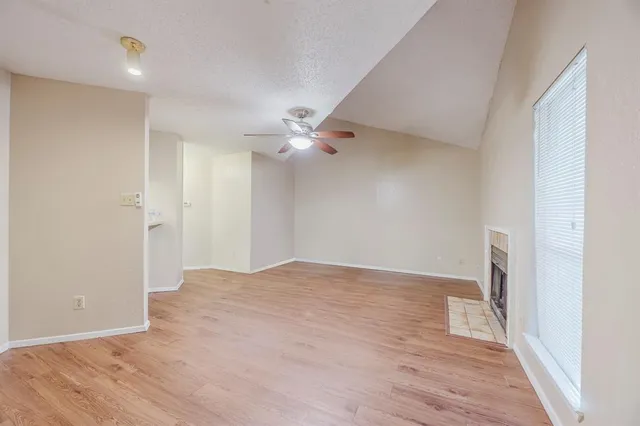 an empty room with a fireplace and wooden floor