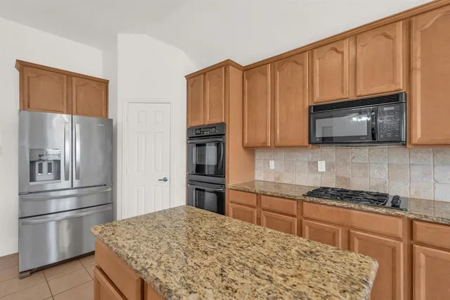 a kitchen with stainless steel appliances granite countertop a refrigerator stove and microwave