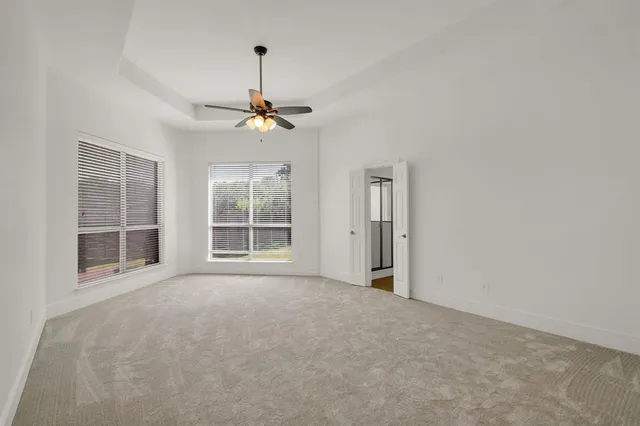 an empty room with windows and chandelier fan
