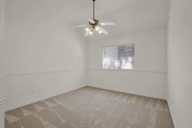 en empty room with windows and chandelier fan
