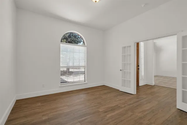an empty room with wooden floor and windows