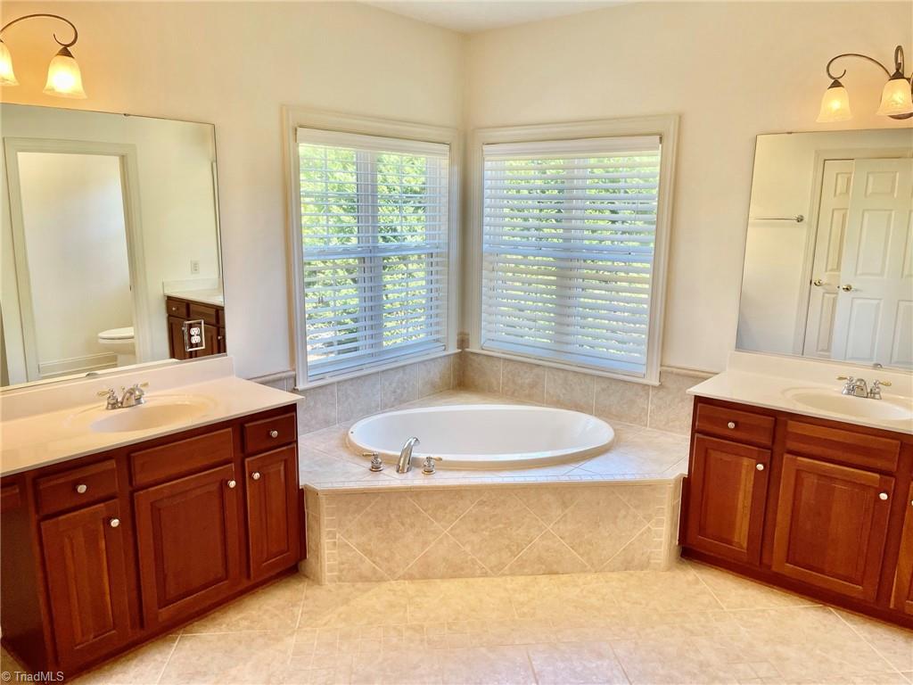 7798 Elizabeth Drive Oak Ridge, NC 27310 - Photo 20 of 26 Extra large primary bath with dual vanities, soaker tub and tile shower