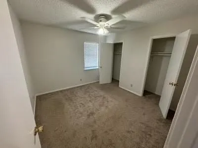 an empty room with windows and fan