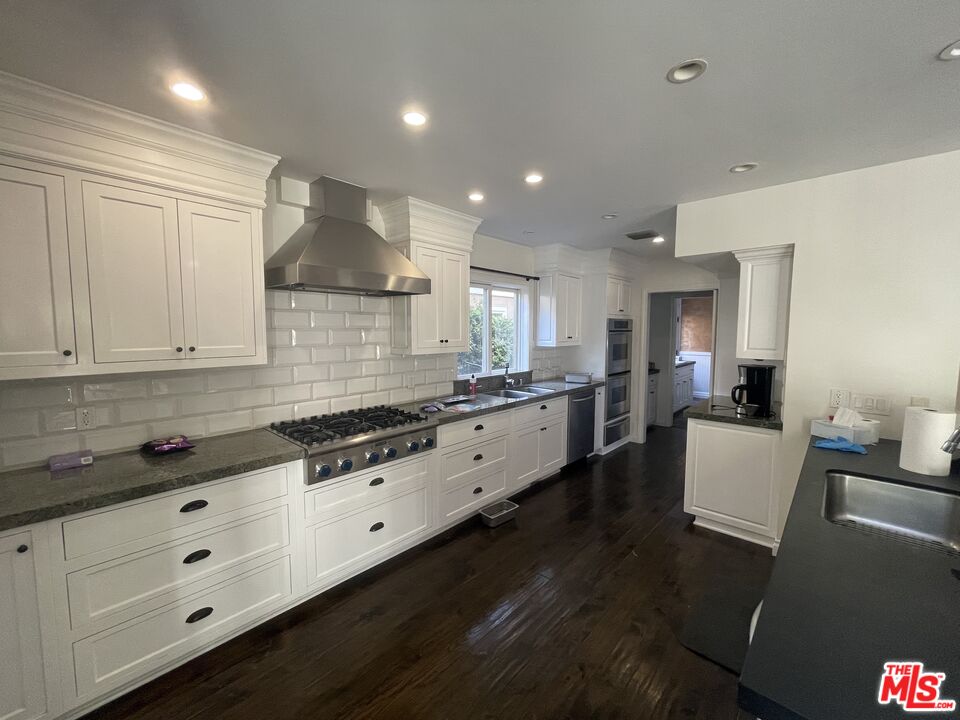 9500 Cresta Drive Los Angeles, CA 90035 - Photo 6 of 13 a large white kitchen with granite countertop a stove a sink a refrigerator and white cabinets with wooden floor
