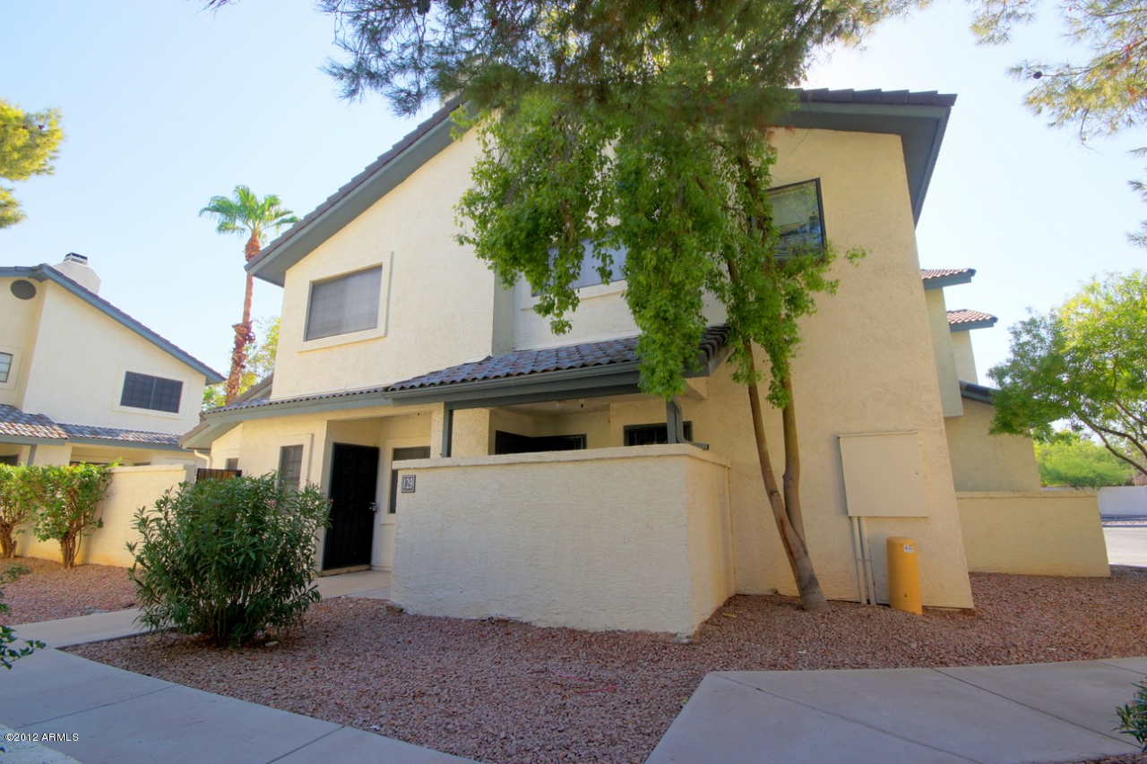 a view of a white house with a yard and plants